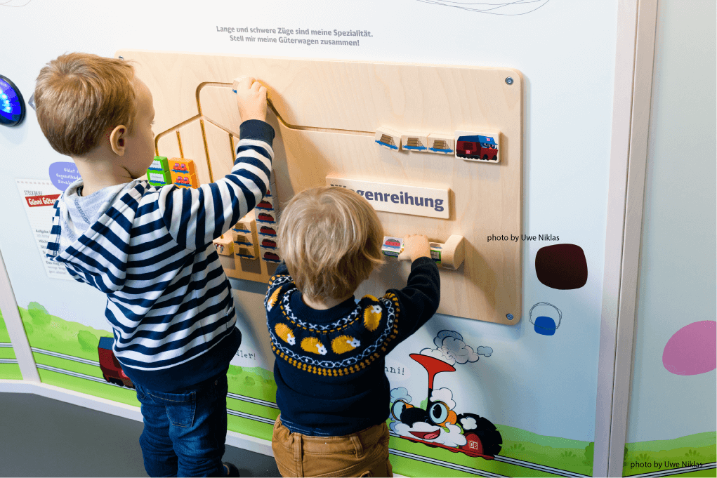 Ladenbau Wand mit Spielelementen und zwei kleinen spielenden Kindern